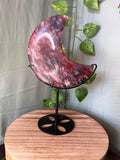 339g natural Fire Quartz crescent moon crystal carving displayed on a black metal stand with deep red hematite inclusions.
