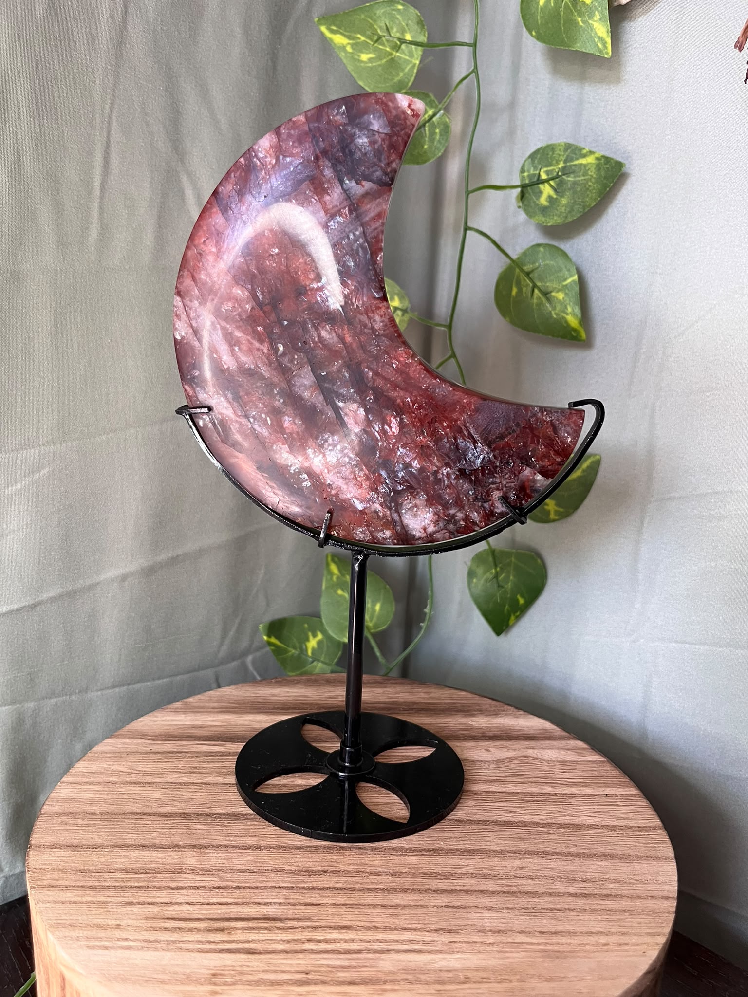 339g natural Fire Quartz crescent moon crystal carving displayed on a black metal stand with deep red hematite inclusions.