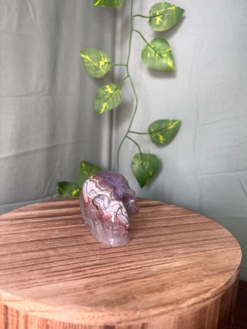 150g natural Amethyst and Agate crystal skull carving featuring intricate lace banding and soft purple quartz tones.