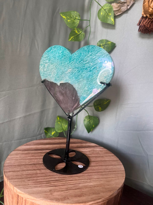 475g natural Amazonite heart crystal with Smoky Quartz matrix displayed on a black metal stand featuring vibrant turquoise-blue colouring.