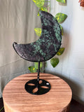 286g UV reactive Ruby Zoisite crescent moon crystal carving on a black metal stand featuring natural green Zoisite, Ruby and dark matrix.