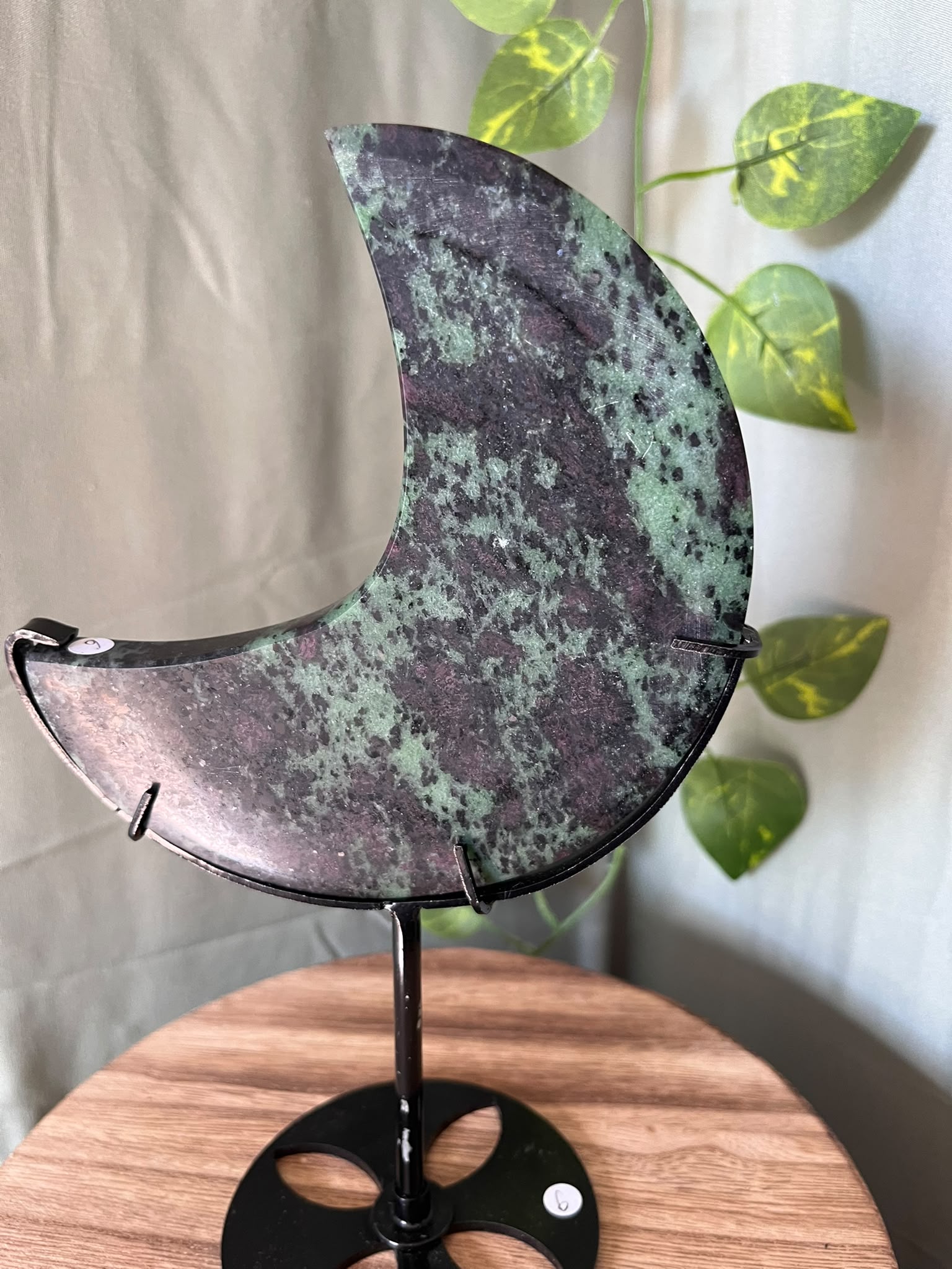 286g UV reactive Ruby Zoisite crescent moon crystal carving on a black metal stand featuring natural green Zoisite, Ruby and dark matrix.