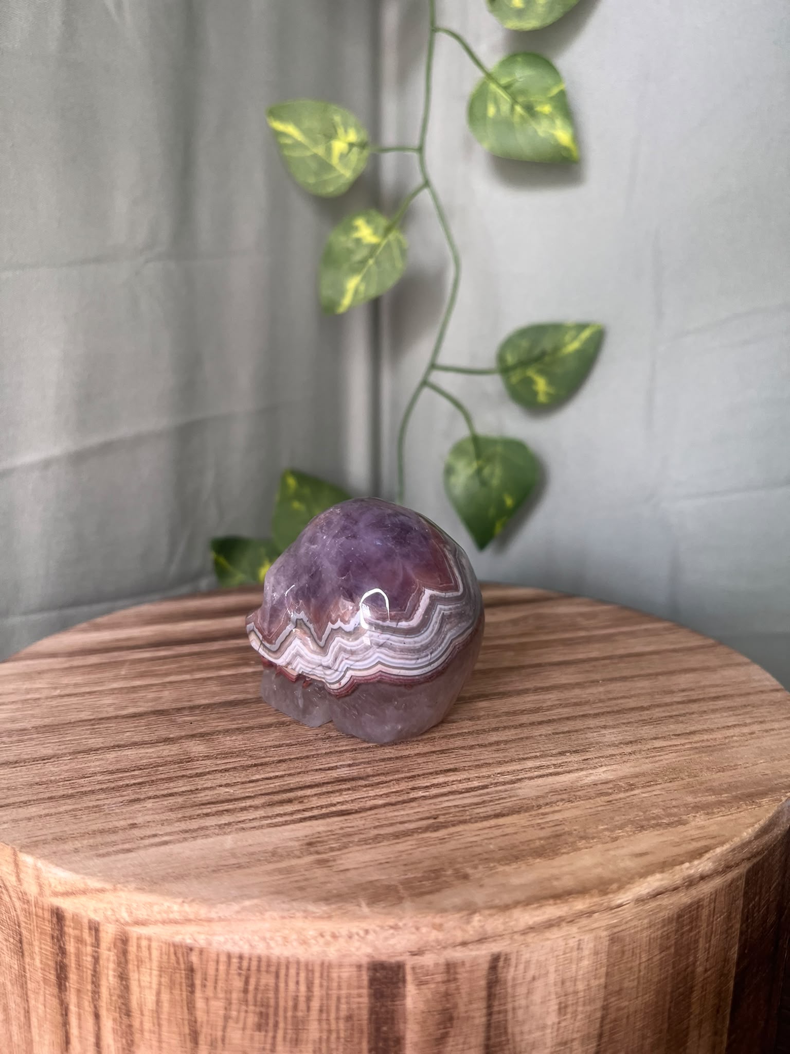 150g natural Amethyst and Agate crystal skull carving featuring intricate lace banding and soft purple quartz tones.