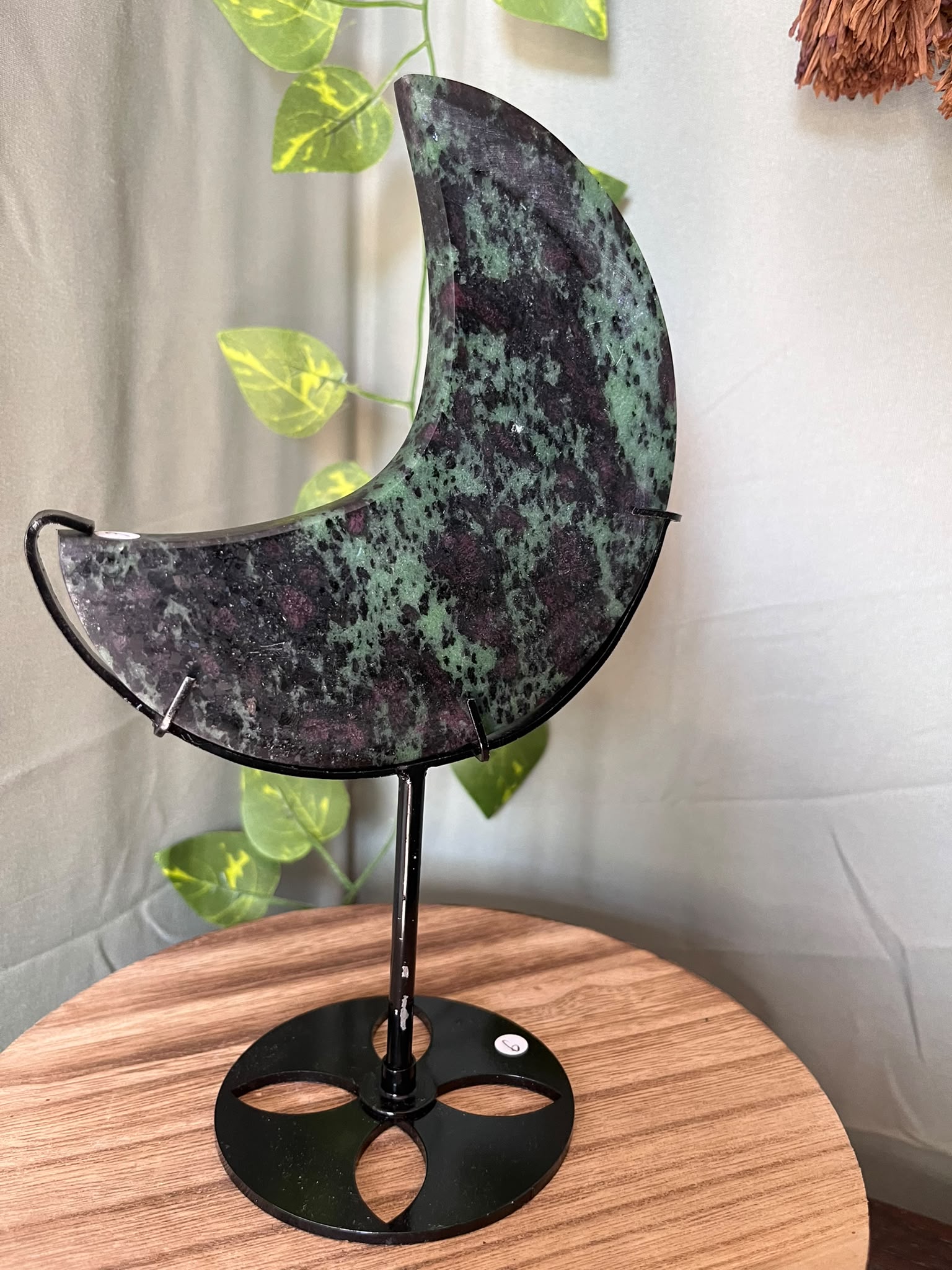 286g UV reactive Ruby Zoisite crescent moon crystal carving on a black metal stand featuring natural green Zoisite, Ruby and dark matrix.